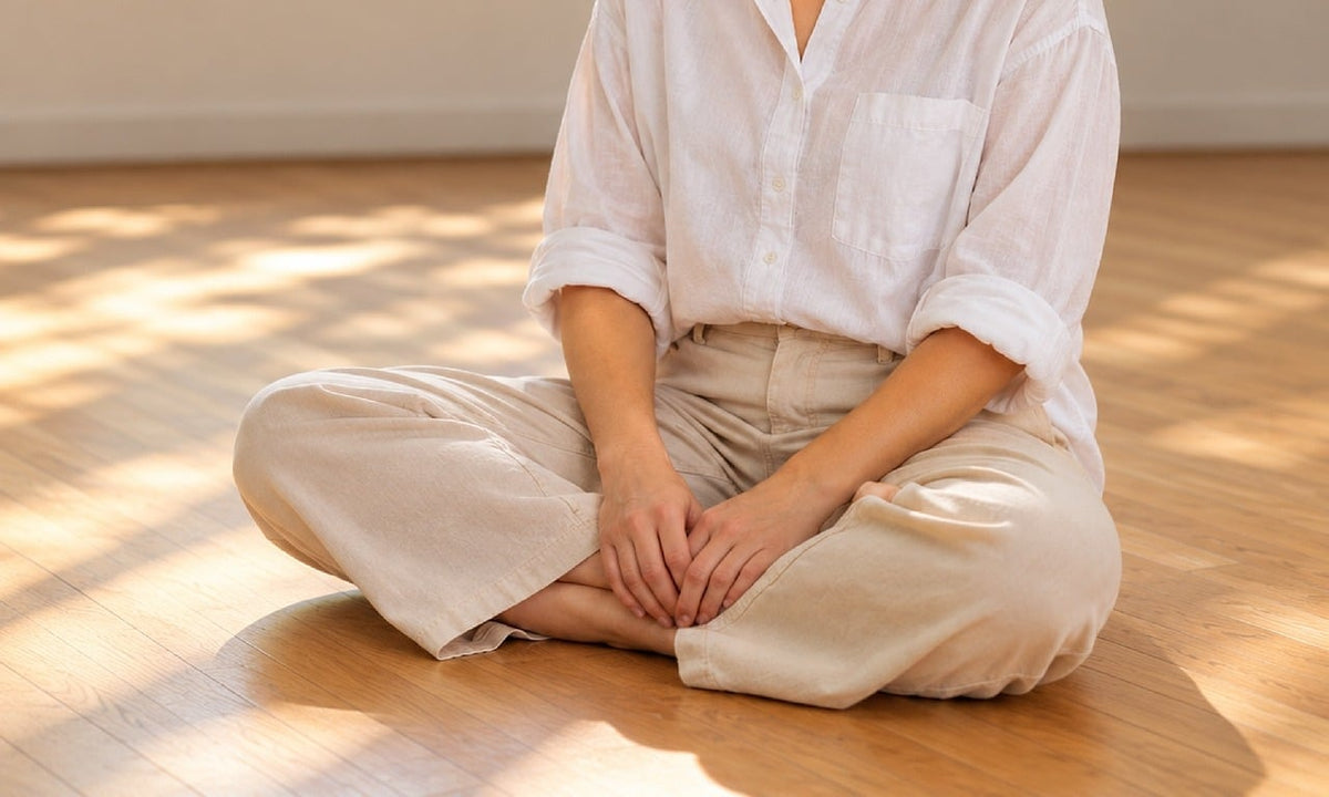 Woman sitting calmly on a wooden floor in a bright room, breathing and relaxing