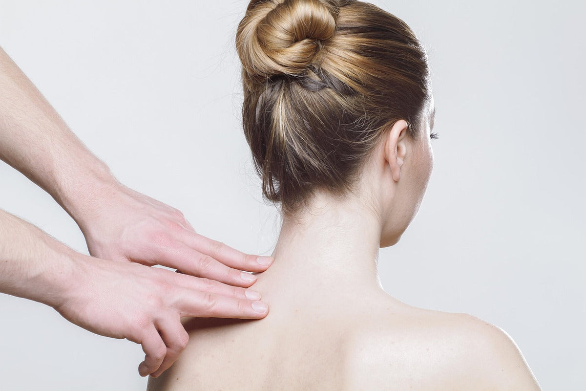 Hands gently massaging the back of a woman's neck and shoulder